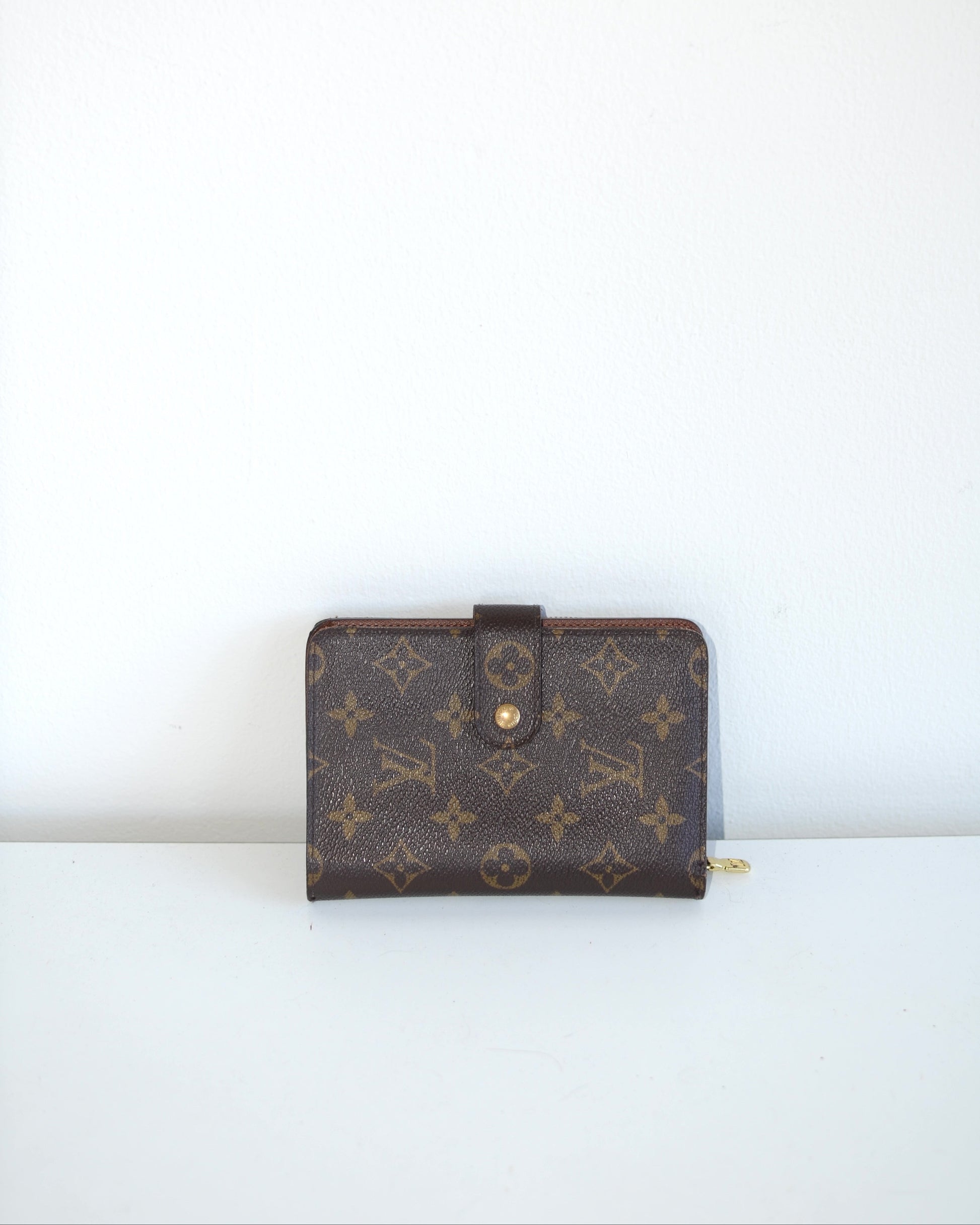 Louis Vuitton compact leather wallet inside compartments and zipper on a white background