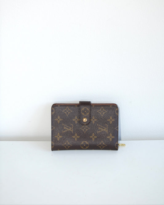 Louis Vuitton compact leather wallet inside compartments and zipper on a white background