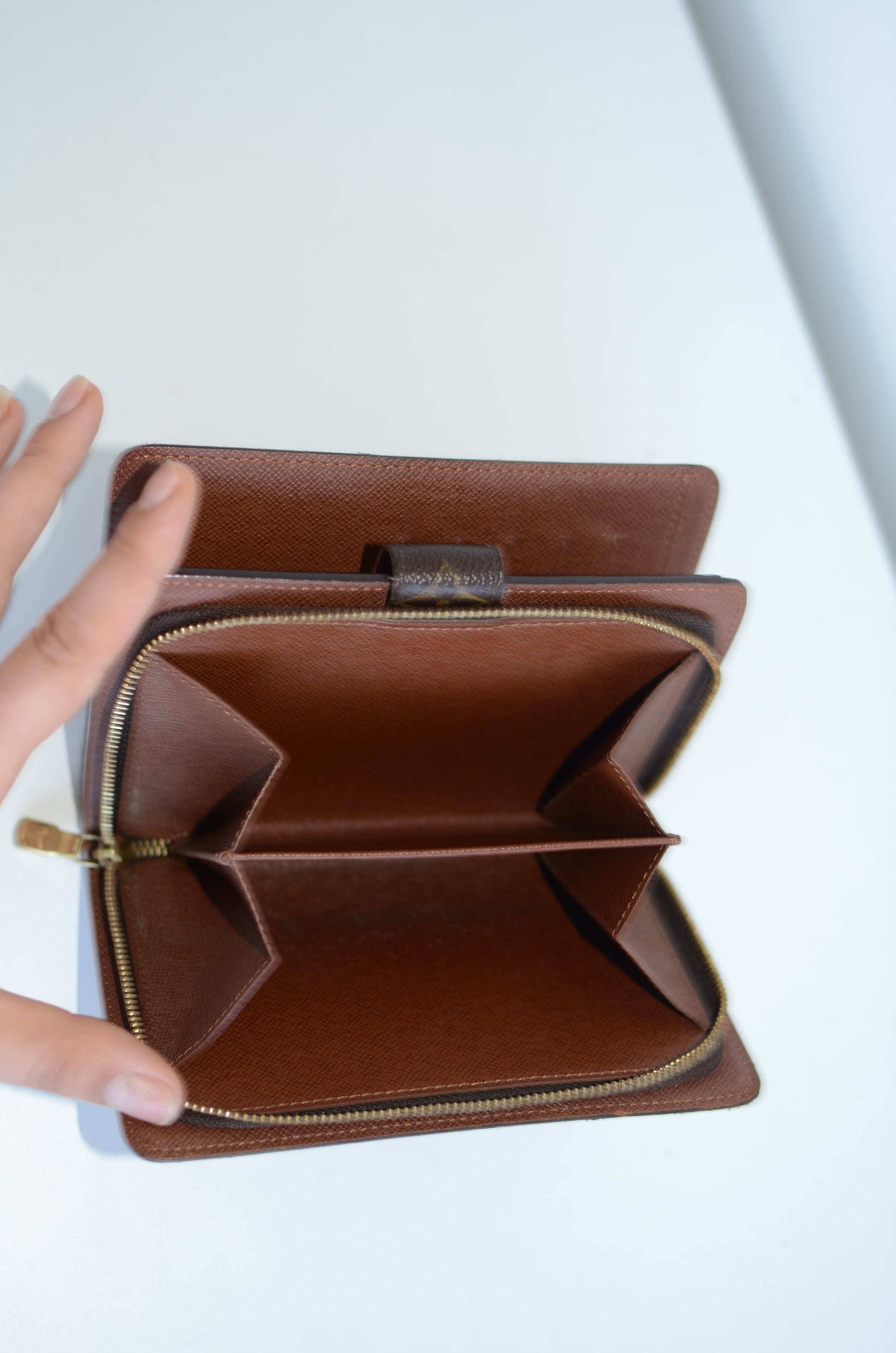 Louis Vuitton compact leather wallet inside compartments and zipper on a white background