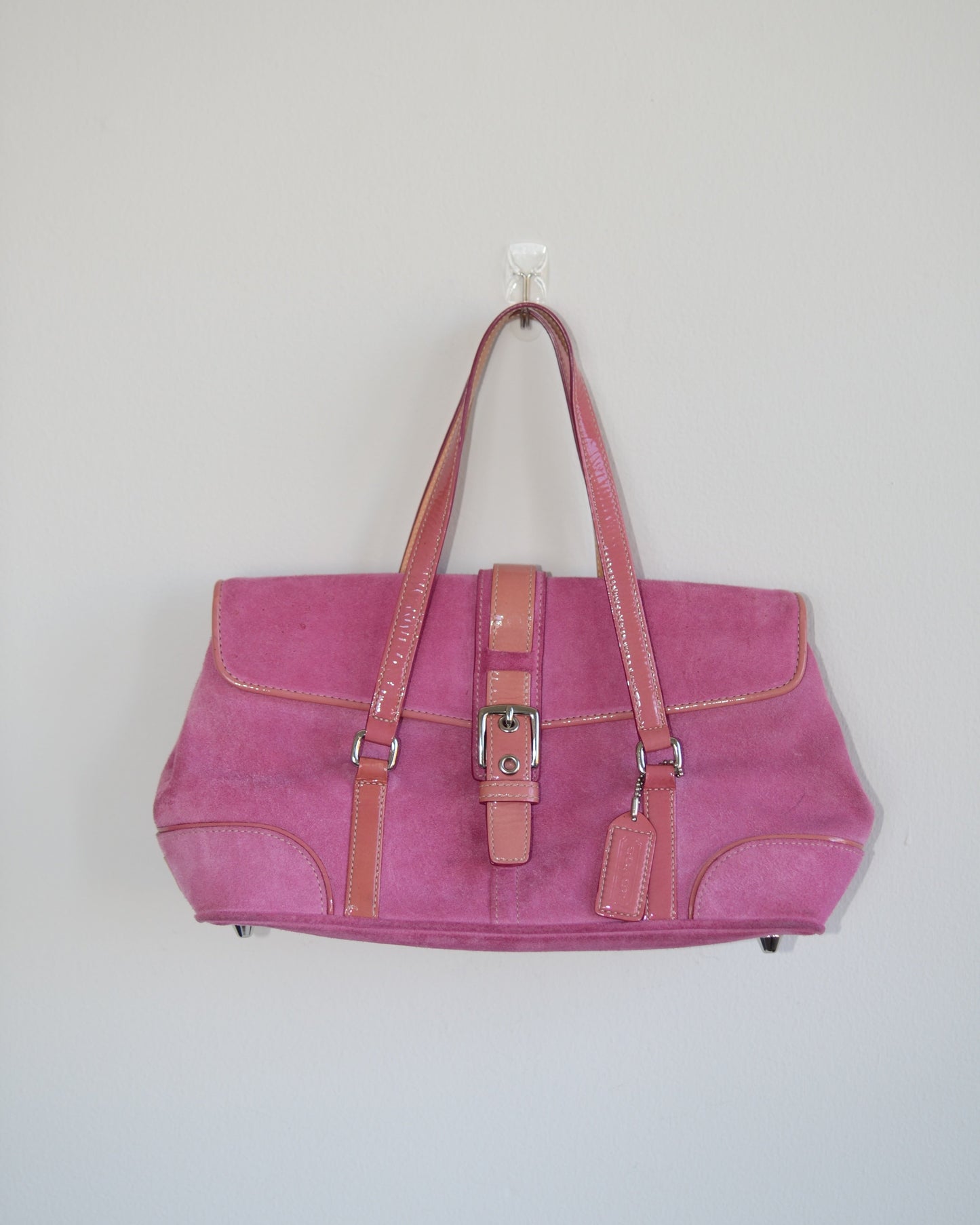 Pink vintage coach handbag with brown accents on a light gray background