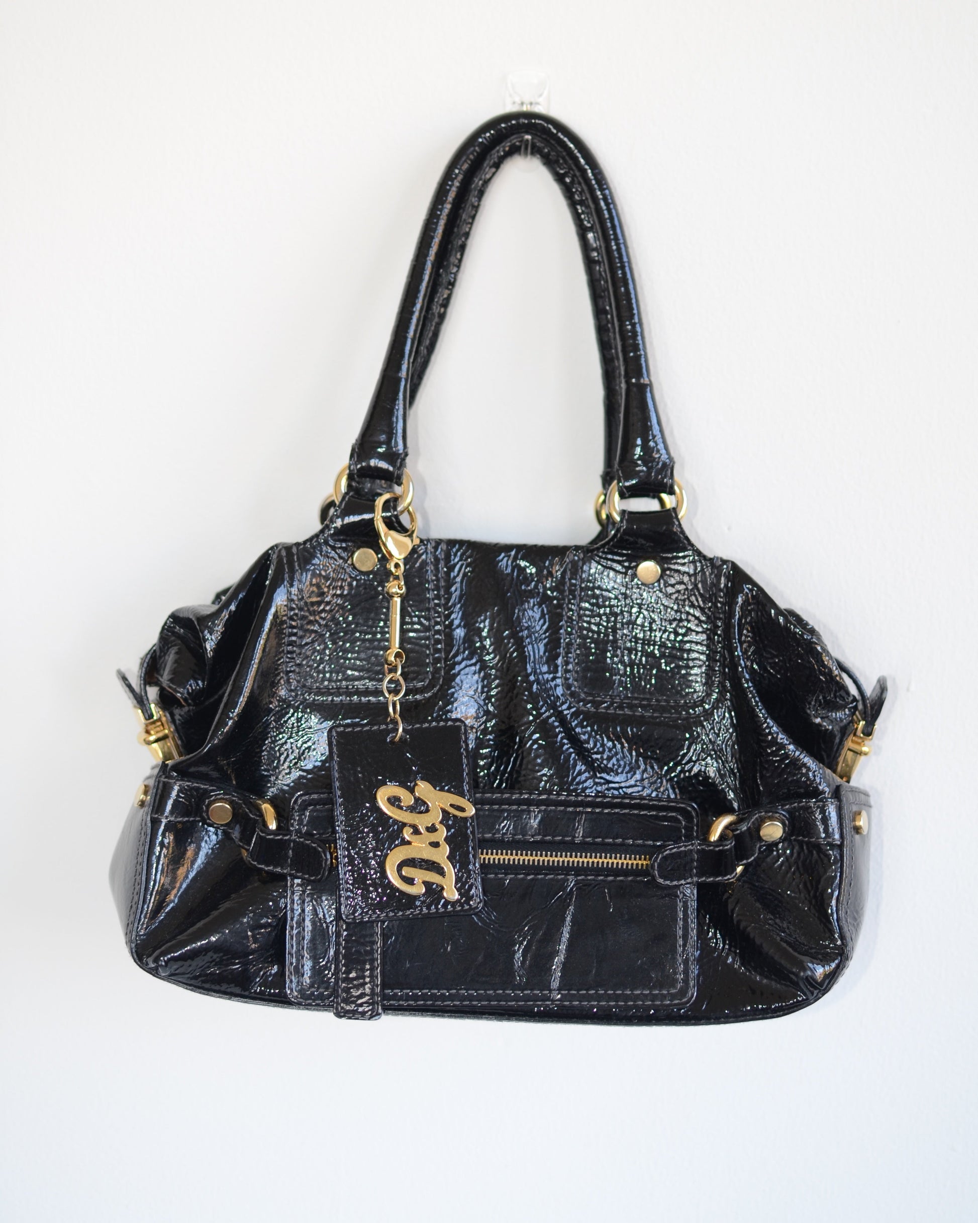 Dolce & Gabbana Black patent leather handbag with gold accents and hardware, with gold D&G logo charm on a white background