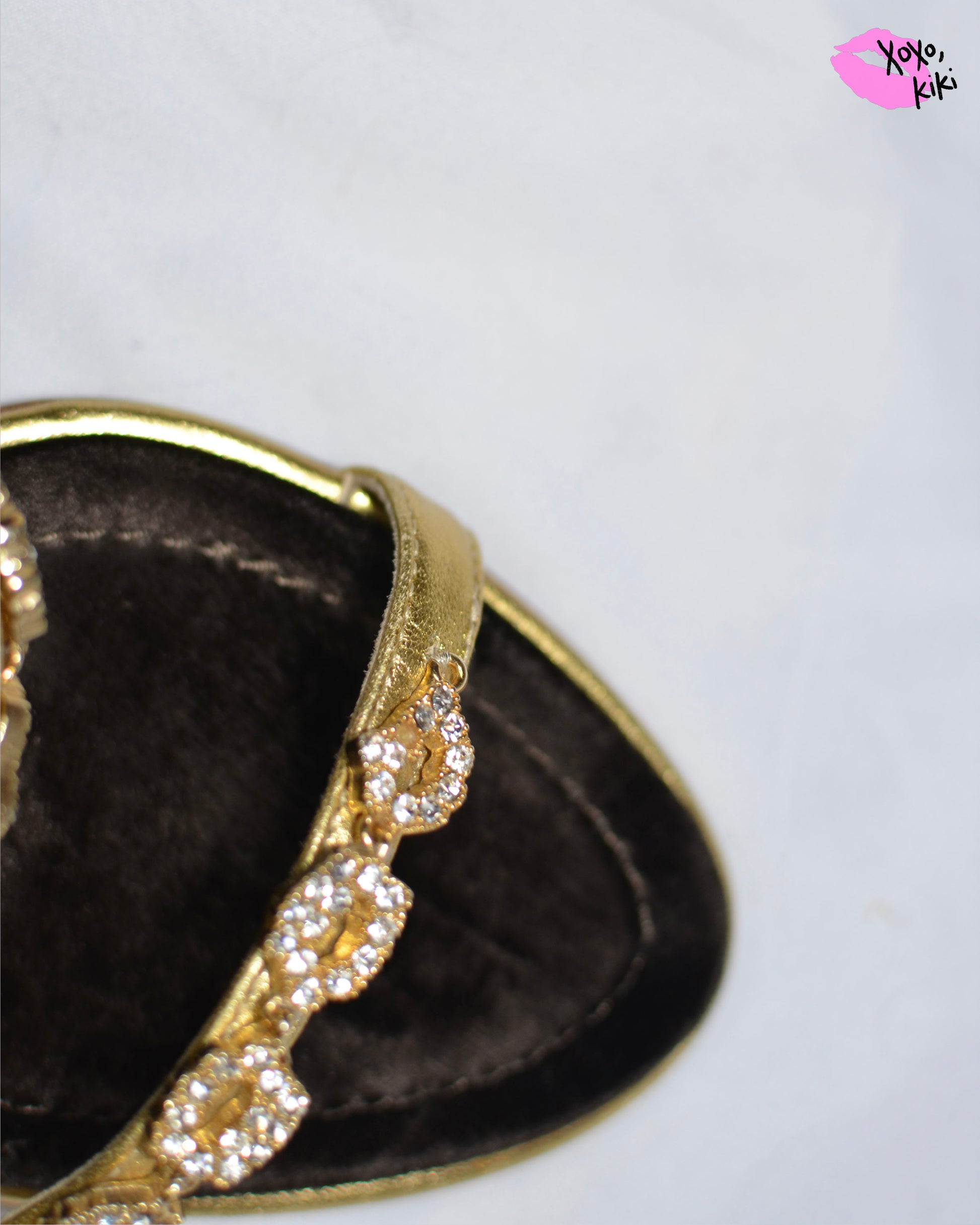 Close up of Gold high-heeled  Giuseppe Zanotti sandals, close up on gold straps with  embellishments and one small crystal missing from strap.